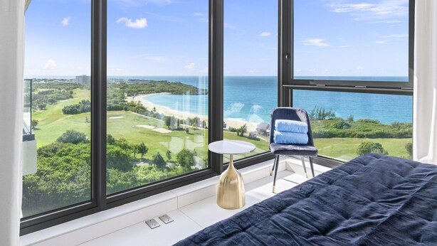 Ein Schlafzimmer mit großem Fenster mit Blick auf Strand und Golfplatz.