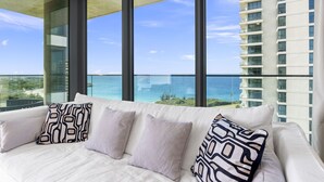 Ein modernes Hotelzimmer mit großem Fenster und Blick auf das Meer sowie ein Hochhaus.