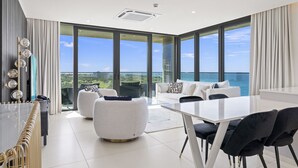 Ein modernes Wohnzimmer mit einem großen Glastisch, weißen Sofas und schwarzen Sesseln.