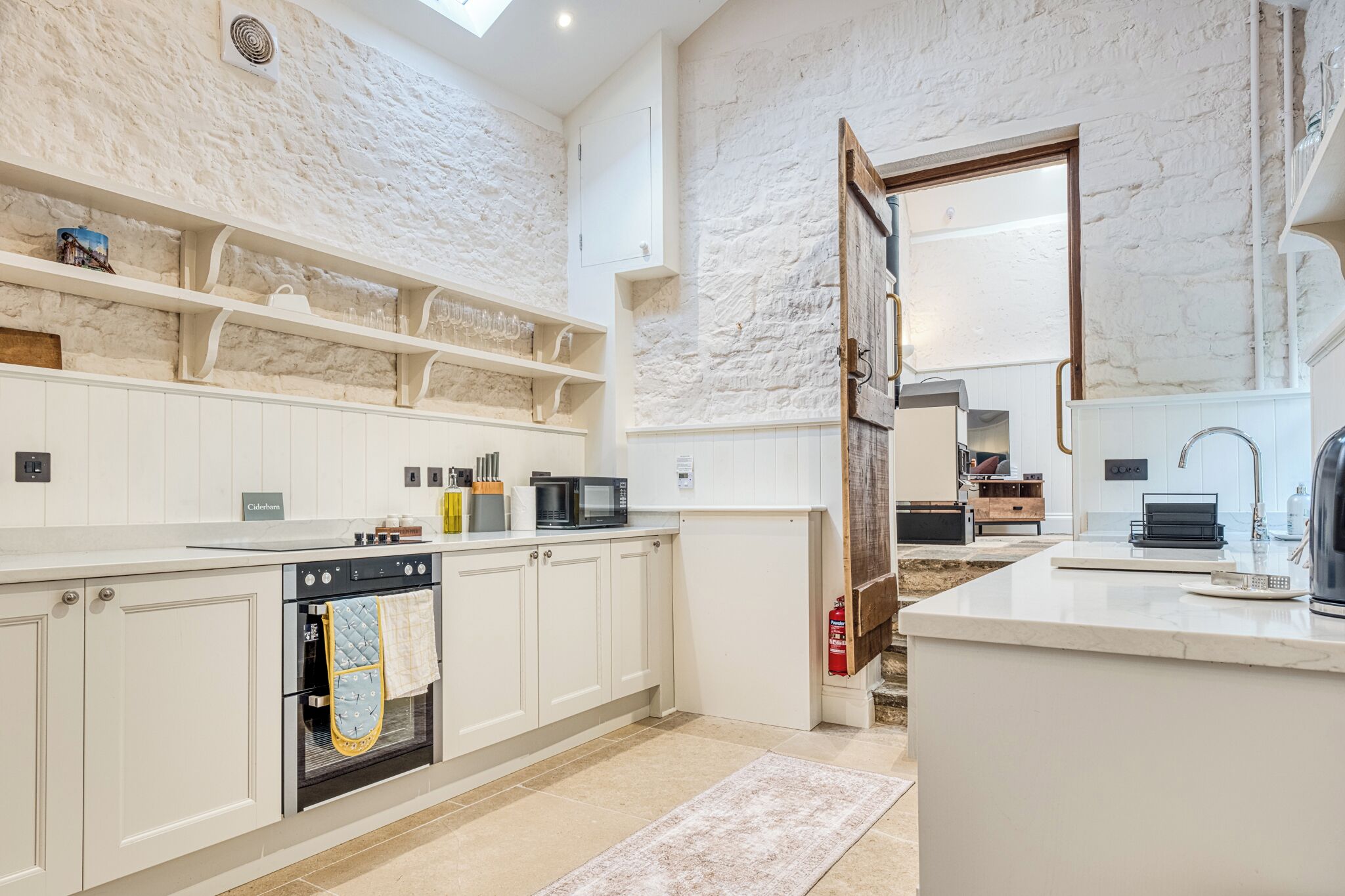 Une cuisine moderne avec des meubles blancs, un four encastré et un grand îlot central doté d’un évier.