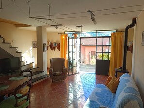 A living room with a sofa, a TV, a fireplace, and a dining area with a table and chairs. - Olivo al Mare - Apartment with Garden and Private Parking in Dolcedo, by HOST4U (Dolcedo)