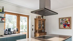 A modern kitchen with a large island, wooden cabinets, and a view of the outdoors. - Panorama Dachstein by Interhome (Rohrmoos)
