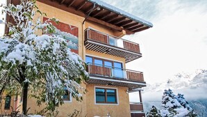 A multi-story building with balconies, surrounded by snow-covered trees and mountains. - Panorama Dachstein by Interhome (Rohrmoos)