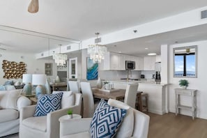 Une cuisine moderne avec des meubles blancs, un îlot central et un coin repas avec des chaises blanches.