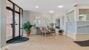 A lobby with a sofa, coffee table, potted plants, and a large mirror.