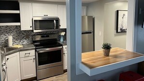 Eine moderne Küche mit weißen Schränken, einem Edelstahlbackofen, einer Mikrowelle und einem Kühlschrank.
