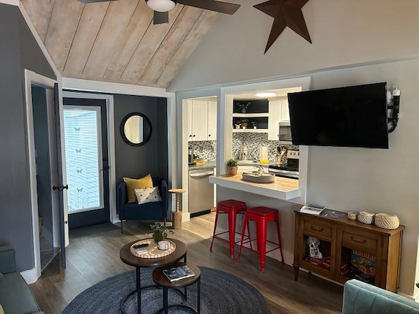 A compact living space with a kitchen, dining area, and a TV mounted on the wall.