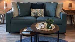 Ein Wohnzimmer mit einer Couch, einem Couchtisch und drei gerahmten Kunstwerken an der Wand.