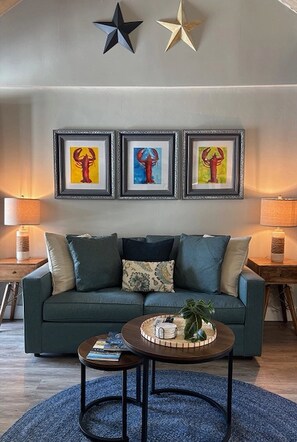 A living room with a sofa, a coffee table, and three framed artworks on the wall.