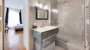 Een moderne badkamer met een douchecabine van glas, een grote spiegel en een wastafelmeubel met een witte wastafel.