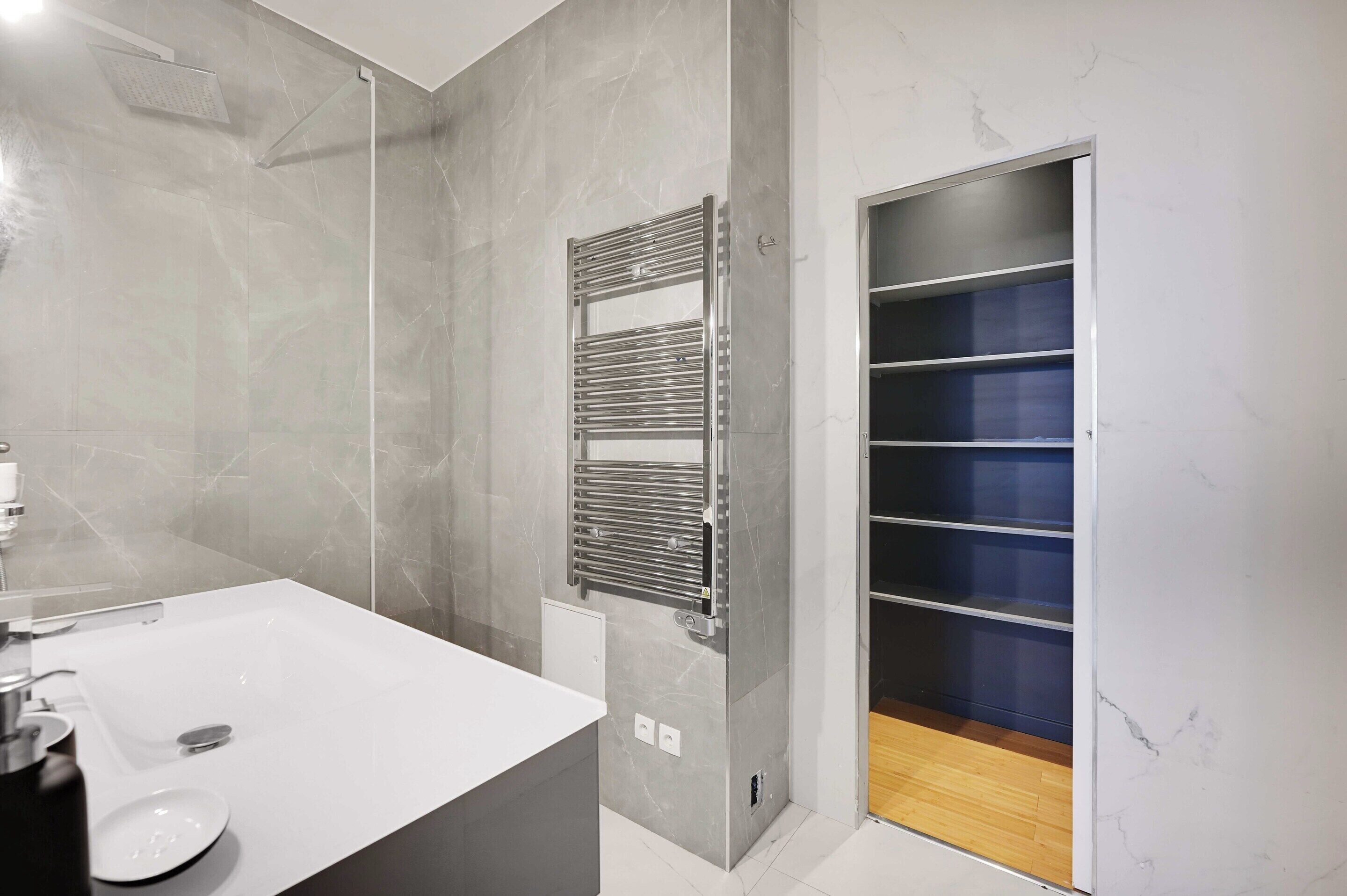 Un baño moderno con lavamanos blanco, toallero y ducha integrada.