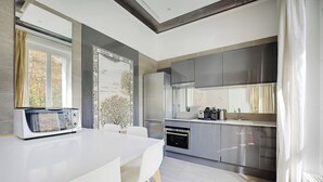 Een moderne keuken met een wit aanrecht, roestvrijstalen apparatuur en een groot raam.