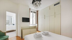 Een slaapkamer met een groot bed, een dressoir, een televisie en een kledingkast.