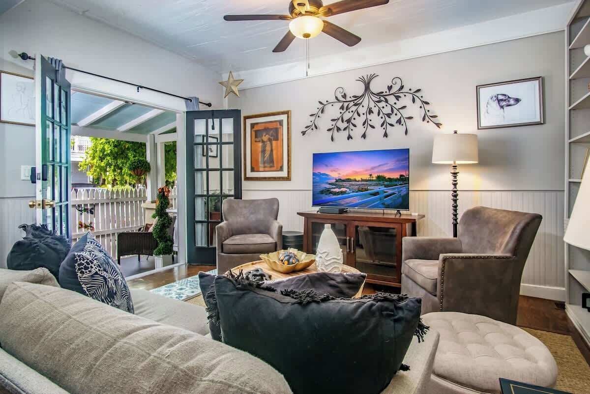 Ein Wohnzimmer mit einer Couch, zwei Sesseln, einem Fernseher und einer Wanddekoration.