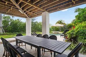 An outdoor patio with a wooden pergola, a dining table, and chairs. - Tideview Haven- 5 bedroom with pool& dock (Key West)