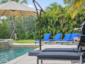 A poolside area with lounge chairs and a grill. - Tideview Haven- 5 bedroom with pool& dock (Key West)
