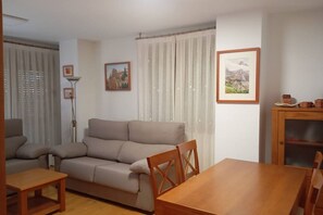 A living room with a sofa, a wooden table, and a cabinet. - 24B03 Apartamento espacioso en Arenas de Cabrales (Cabrales)