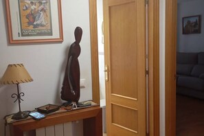 A room with a wooden door, a framed picture on the wall, a lamp, and a table with a smartphone. - 24B03 Apartamento espacioso en Arenas de Cabrales (Cabrales)