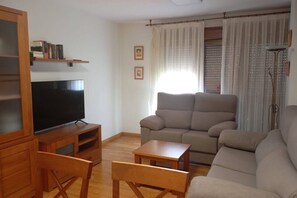 Sala de estar com televisão, sofá e móveis de madeira.