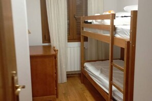 A small, narrow room with a wooden bunk bed, a wooden desk, and a radiator. - 24B03 Apartamento espacioso en Arenas de Cabrales (Cabrales)