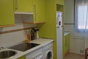 Uma cozinha compacta com máquina de lavar embutida, pia e bancada com diversos objetos.