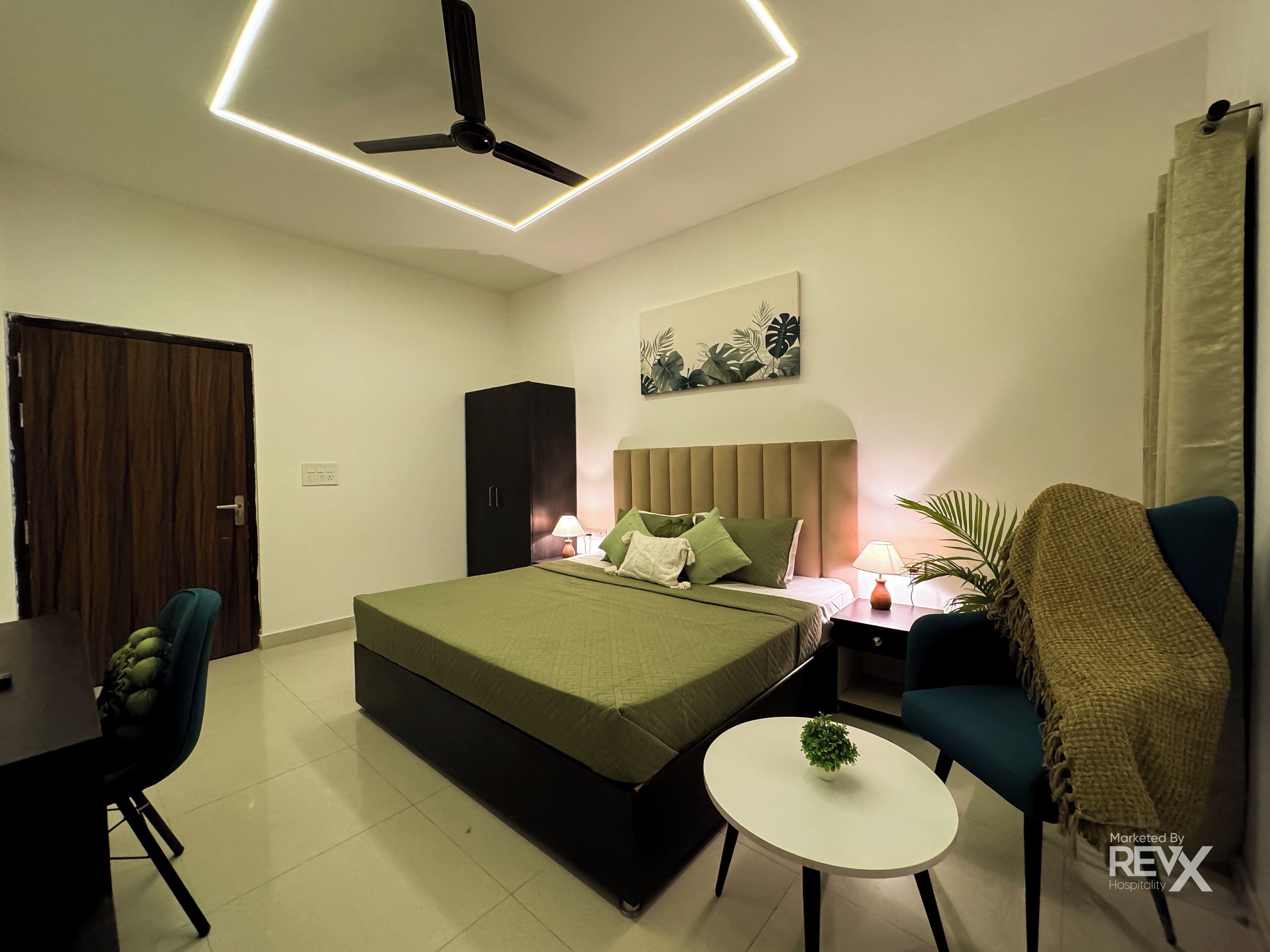 Een moderne slaapkamer met een bed, nachtkastje, lamp, stoel en plafondventilator.