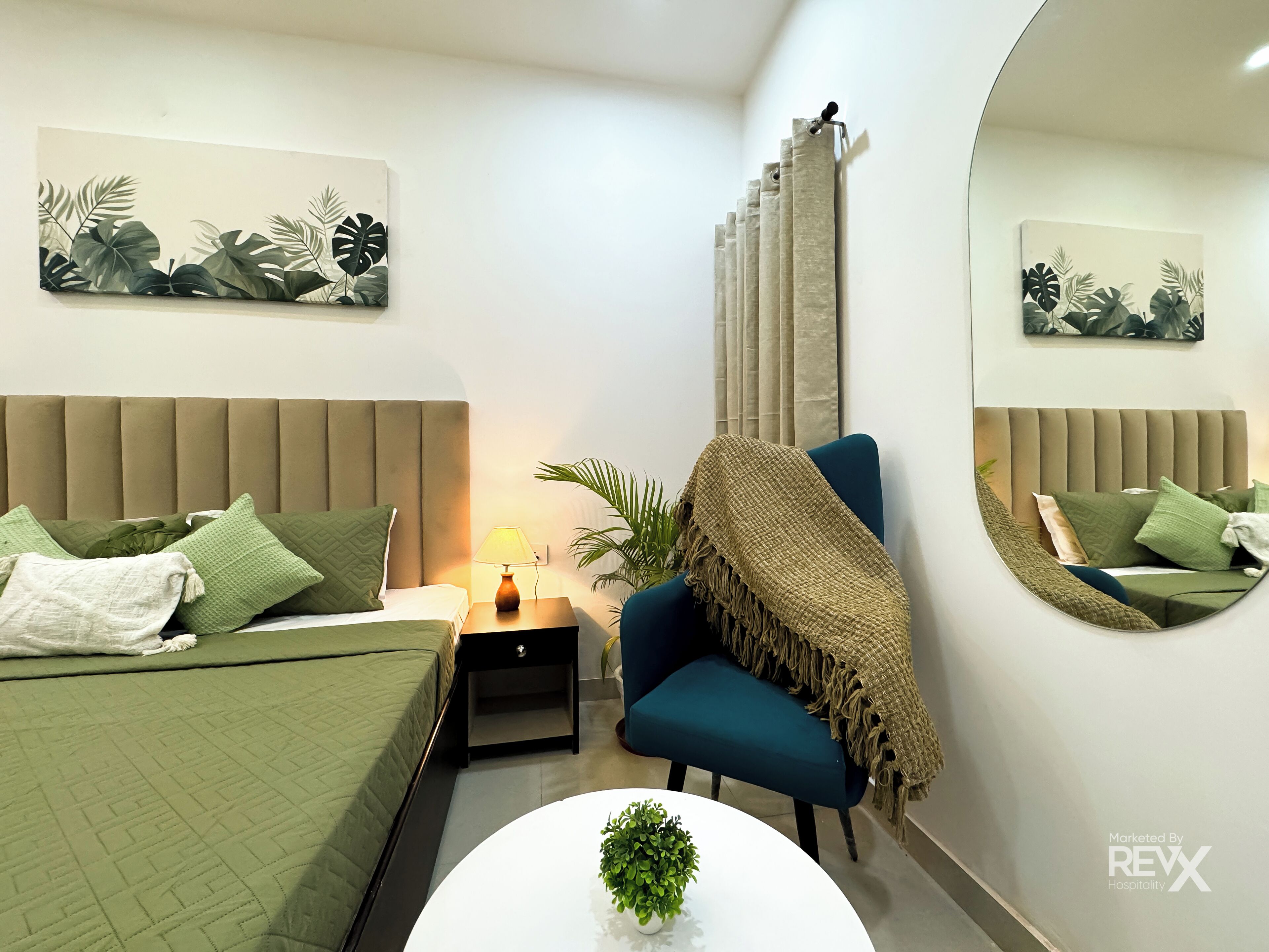 A modern bedroom with a bed, bedside table, lamp, chair, and a small table with a plant.