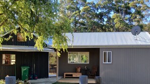 A residential property with a fenced yard, a wooden deck, and a house with a satellite dish. - cosy cottage with wood heater, surrounded by bushland (Middleton)