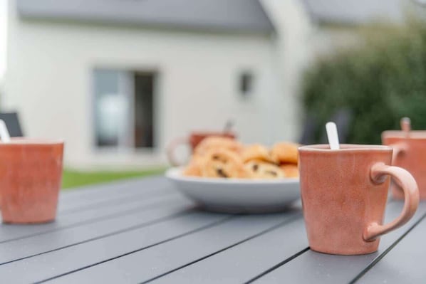 A table with three pink mugs and a bowl of cookies.