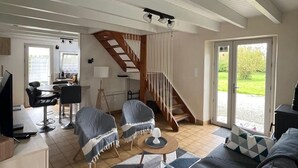 A spacious living area with a staircase, a dining area, and a view of the outdoors. - Ty Manoa - Pretty house 50m from the sea (Landéda)