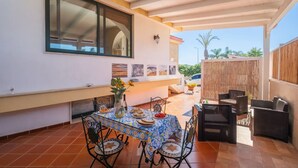 An outdoor patio with a table set for dining, surrounded by wicker furniture. - Sirena Apartment in Luxury Villa with Shared Pool (Scala di Furno)
