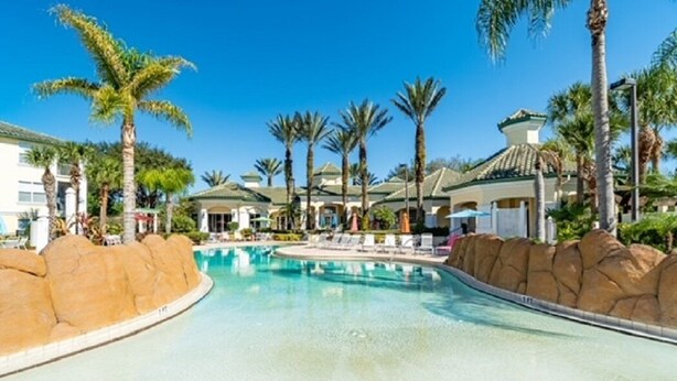 A resort pool area with palm trees, lounge chairs, and a clear blue sky. - 12-204 Legacy Dunes, Free WiFi, Heated Pool, Close to Disney (Kissimmee)