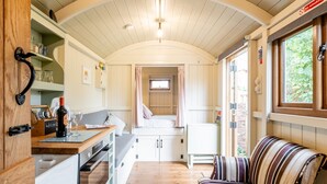 A compact, well-lit kitchen with a built-in oven, a dining area with a table and chairs, and a cozy seating area with a striped sofa.