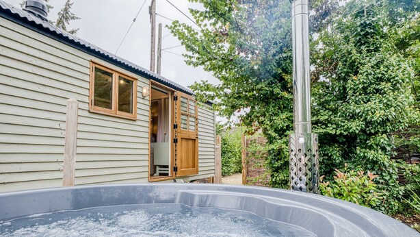 A house with a hot tub in the backyard, wooden doors, and a metal pole.