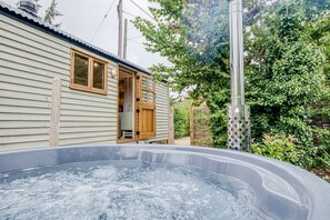 A house with a hot tub in the backyard, wooden doors, and a metal pole.