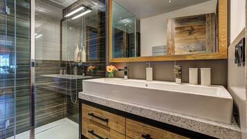 Une salle de bain moderne avec un grand miroir, un meuble-lavabo à deux vasques et une cabine de douche en verre.