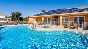 Une piscine avec des chaises longues et un bâtiment équipé de panneaux solaires.