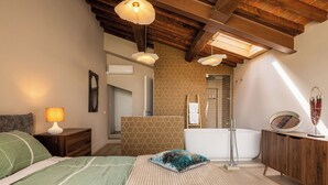 Ein Schlafzimmer mit einem Bett, einer Nachttischlampe und Blick ins Badezimmer.