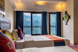 A hotel room with two beds, a balcony with a view of mountains, and an air conditioning unit.