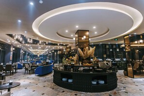 En moderne hotellobby med et cirkulært barområde, siddepladser og en trappe til øverste etager.