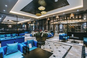 A modern lobby with blue seating, a large decorative plant, and a patterned floor. - Sapa Charm Hotel (Sa Pa)