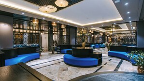 A modern lobby with blue seating, a central round table, and decorative lighting. - Sapa Charm Hotel (Sa Pa)