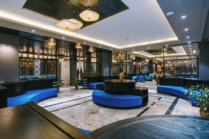 Un lobby moderno con asientos azules, una mesa redonda central e iluminación decorativa.