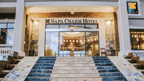 A hotel entrance with a staircase leading up to it, a sign reading 'SAPA CHARM HOTEL,' and a logo above the entrance. - Sapa Charm Hotel (Sa Pa)