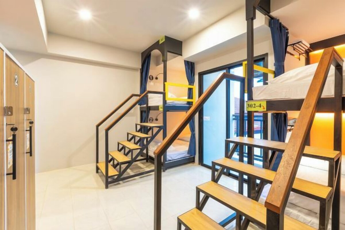 Un dormitorio con literas, escaleras de madera y una puerta con el número.