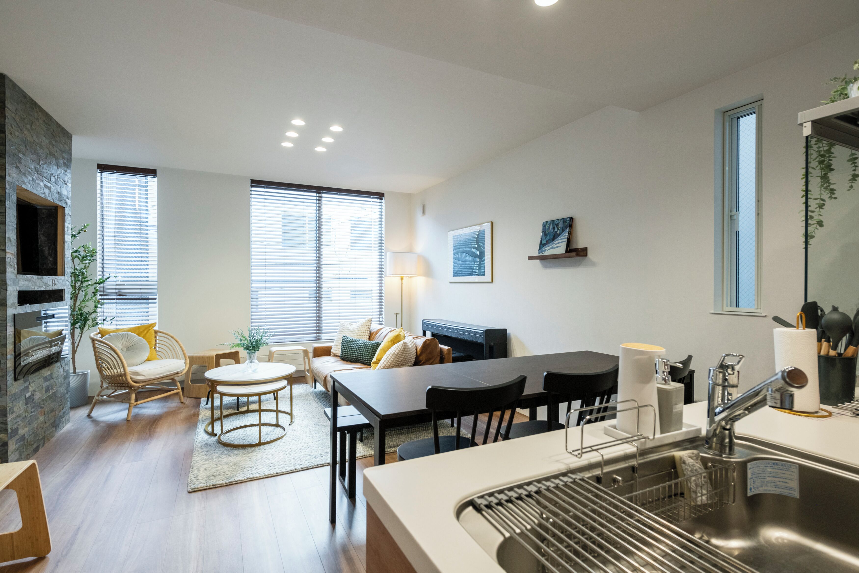 A modern kitchen with a dining area, a built-in stove, and a large window.