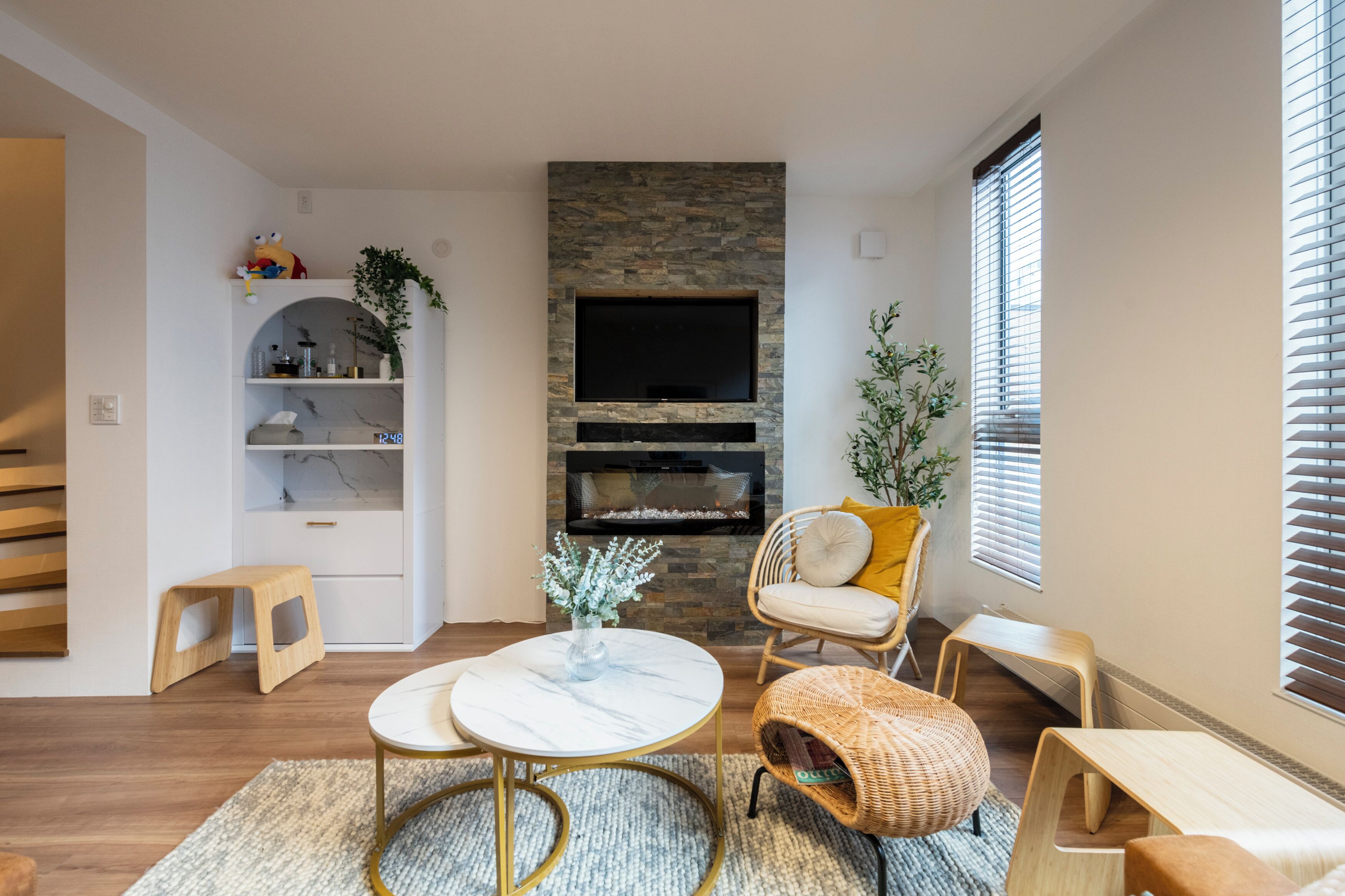 A modern living room with a stone fireplace, a television, and comfortable seating.