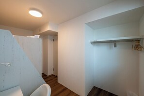 Une salle de bain moderne avec une douche, des toilettes et un lavabo. Le sol est en bois et le mur est blanc.
