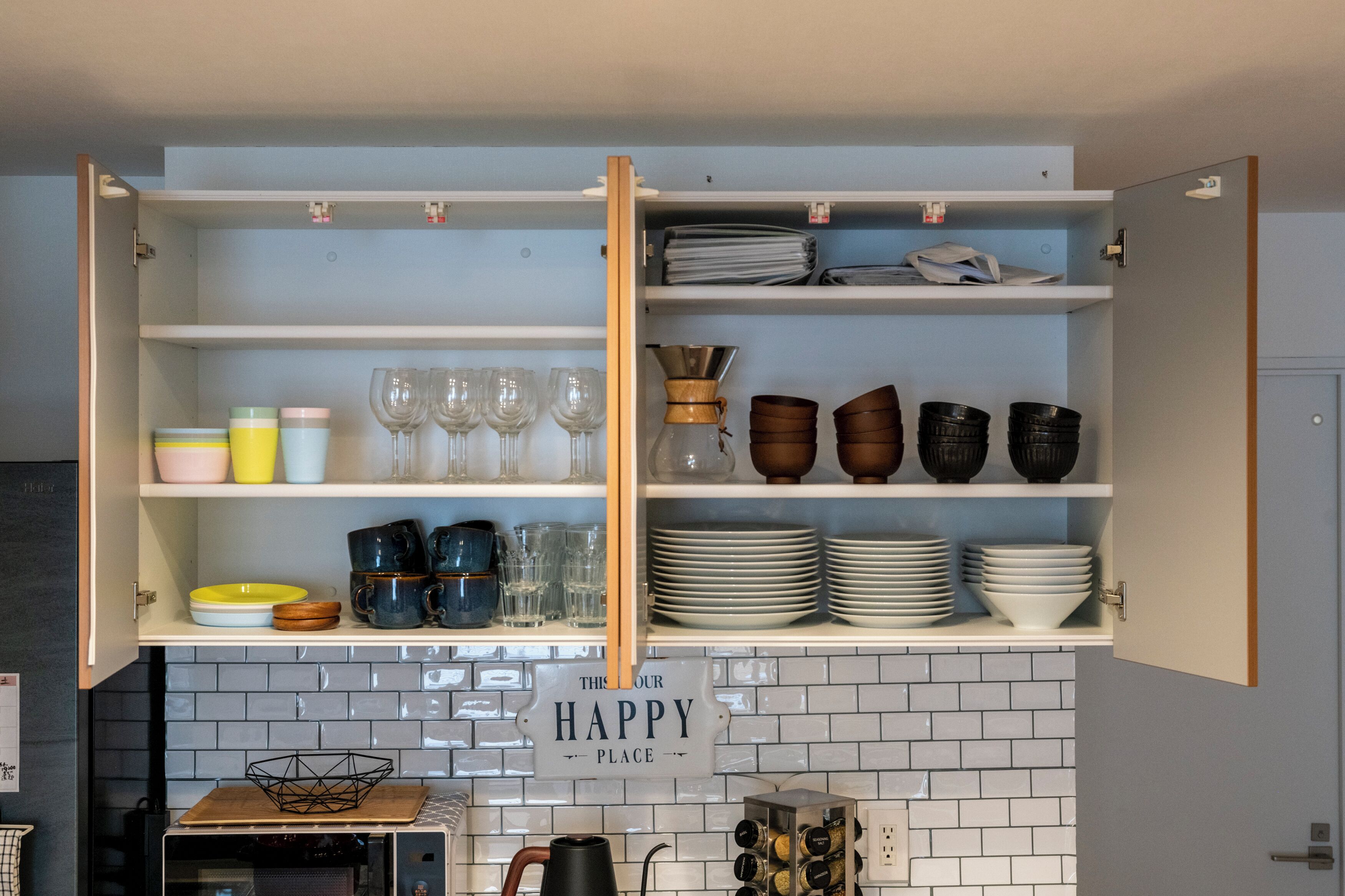 A kitchen with open cabinets displaying various dishes, glasses, and a coffee maker.