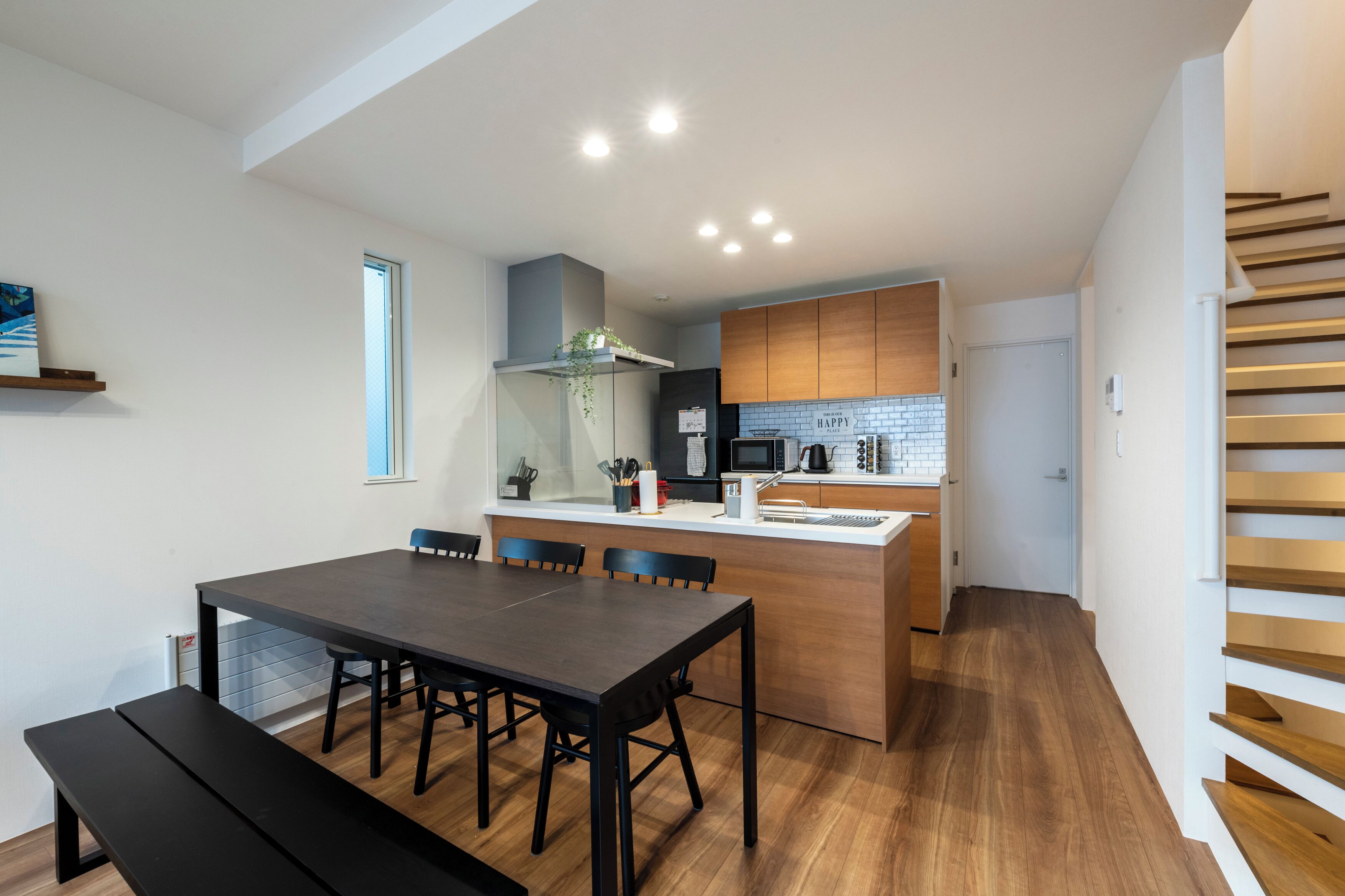 A modern kitchen with wooden cabinets, a central island, and a dining area with a bench.